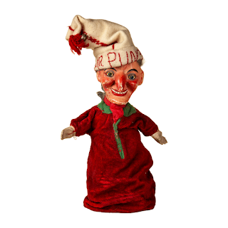 A Mr Punch glove puppet, with ceramic head and slightly crazed expression, white hat with Mr Punch embroidered on it, and a long red gown