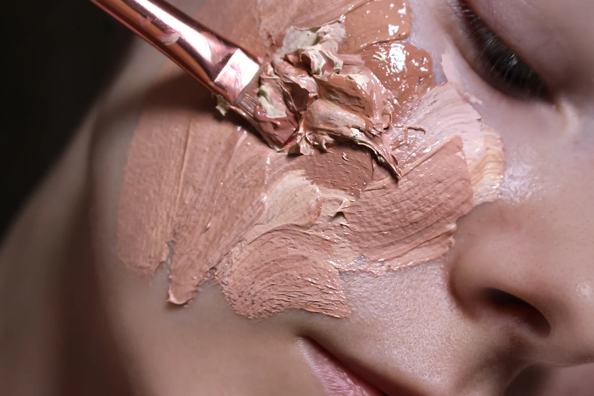 close-up of woman's face with a cakey foundation and concealer applied to the skin with brush