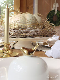 Thanksgiving gold and white table setting with cinderella pumpkin on a white and gold vine base