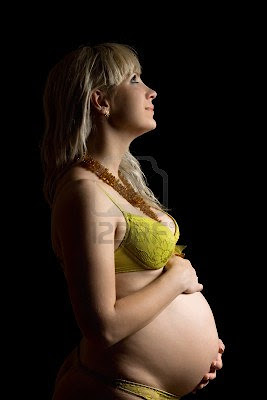 happy pregnant young woman in yellow lingerie isolated on black