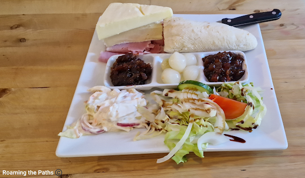 Ploughmans at the Three Mariners with crusty baggette, MAture Cheddar cheese, ham, Brie, pickled onions,  Ploughmans Pickle, Chutney, Colslaw and salad.
