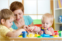 Eine Frau mit zwei Kindern, die auf verschieden gefärbte und geformte Klötzchen blicken und diese greifen.