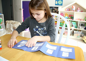 After creating a quick accordion-fold construction paper booklet of various types of snowflakes for "Frosty Figures," Tessa decorated the front cover with snowflakes drawn with glitter glue.