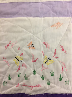 A quilt square with embroidered butterflies and purple trim