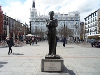 Estatua en bronce de Lorca sobre un pedestal y placa conmemorativa. Al fondo el hotel Me Madrid.