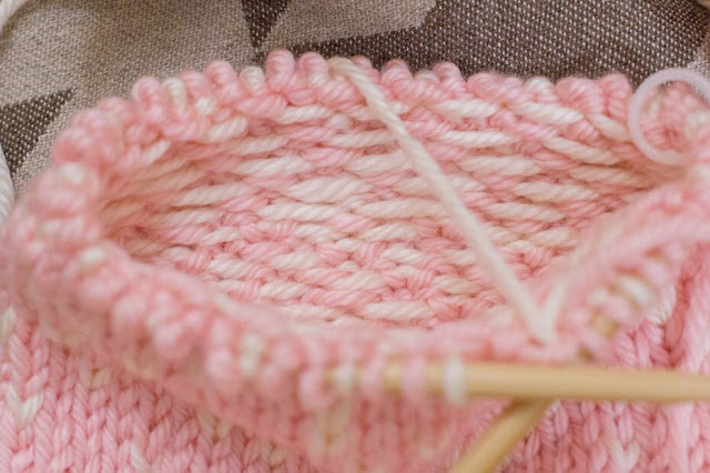 Focused on inside view of the light pink and cream fair isle knitting hat in the works on circular knitting needles.