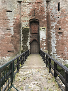 A photo looking along the drawbridge of Caerlaverock Castle to the door to enter the building.  The wooden door is closed.  Photo by Kevin Nosferatu for the Skulferatu Project.