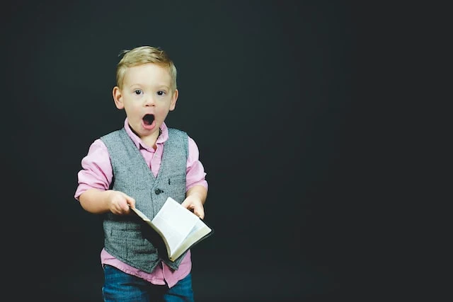 a stock photo from unsplash of a surprised child with a book