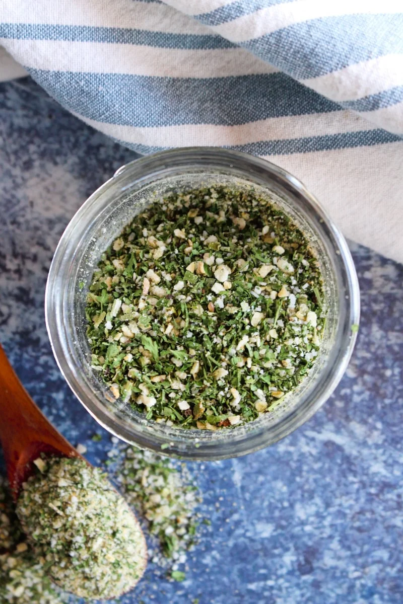 Top view of homemade ranch mix in a small mason jar on a blue background.