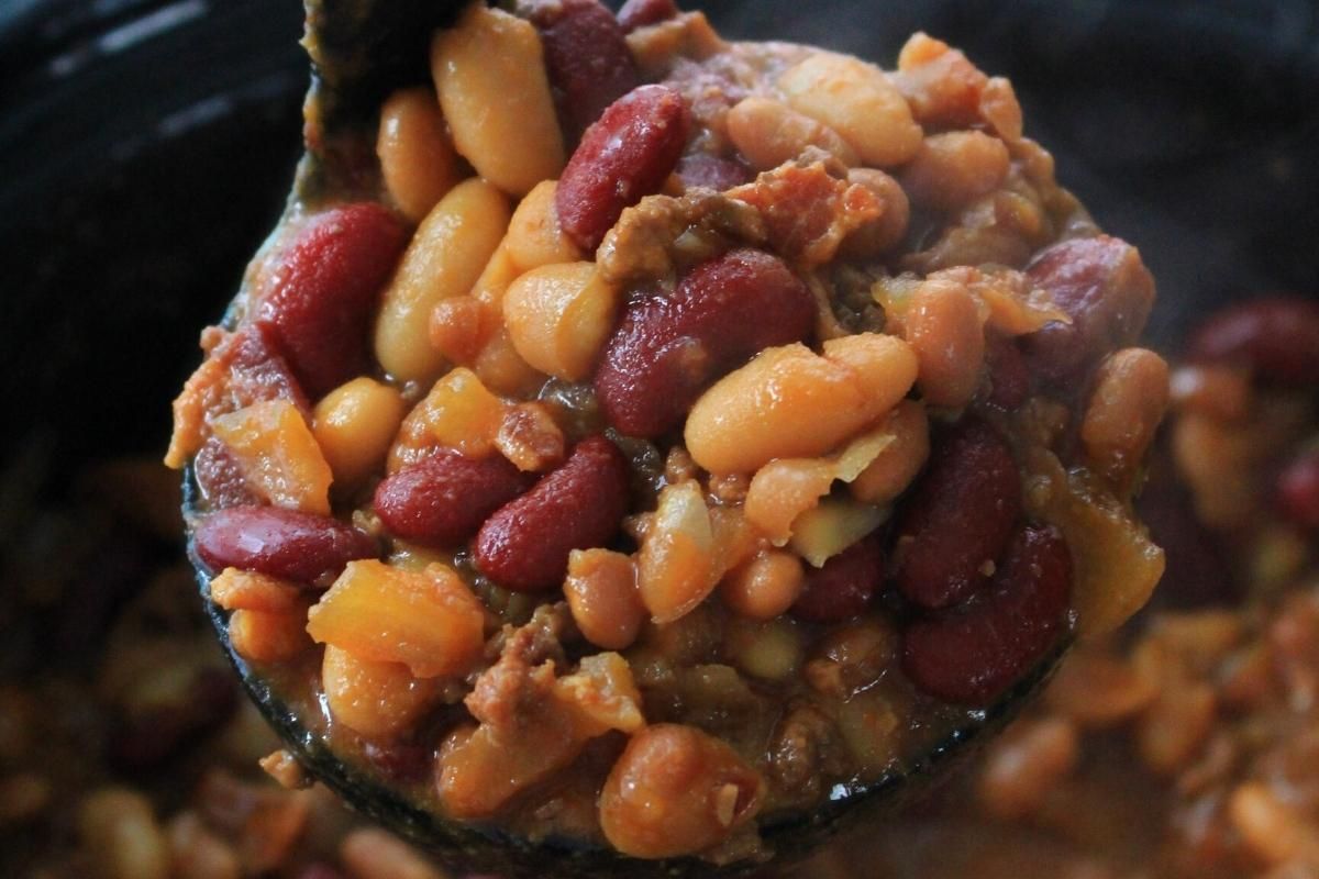 A large ladle overflowing with Cowboy Beans.