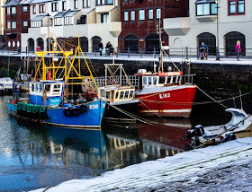 Photo of colourful fishing boats in Maryport Harbour with a dusting of snow