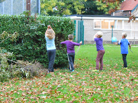 boys beating a rivet hedge with sticks making a camp den in the park with fallen branches