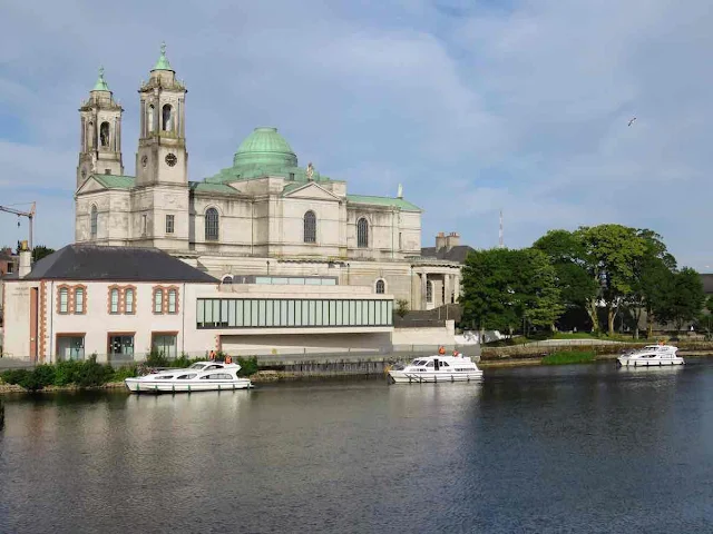 Things to do in Athlone Ireland: Boats on the River Shannon in front of a church