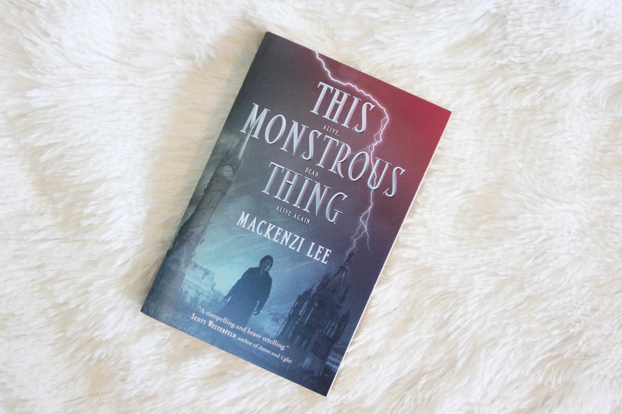 This Monstrous Thing by Mackenzi Lee. Book lying on white fluffy blanket. Blogger's Bookshelf.