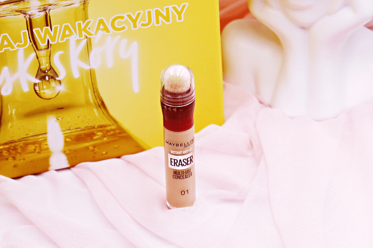 Innowacyjny korektor Maybelline Instant Eraser prezentowany na delikatnym różowym tle z wyraźnym żółtym napisem w tle oraz białym manekinem z kwiatową koroną, podkreślając jego działanie maskujące i anty-agingowe