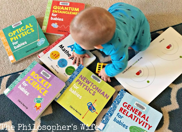 A baby is crawling among a variety of books, including Optical Physics for Babies, Quantum Entanglement for Babies, Rocket Science for Babies, Newtonian Physics for Babies, and General Relativity for Babies.