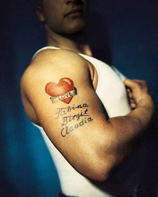 A man showing his big red heart tattoo on his upper arm with her girl