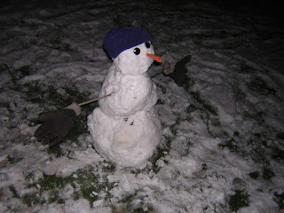 [icture of medium sized snowman with knit cap, button eyes, carrot nose, and stick arms