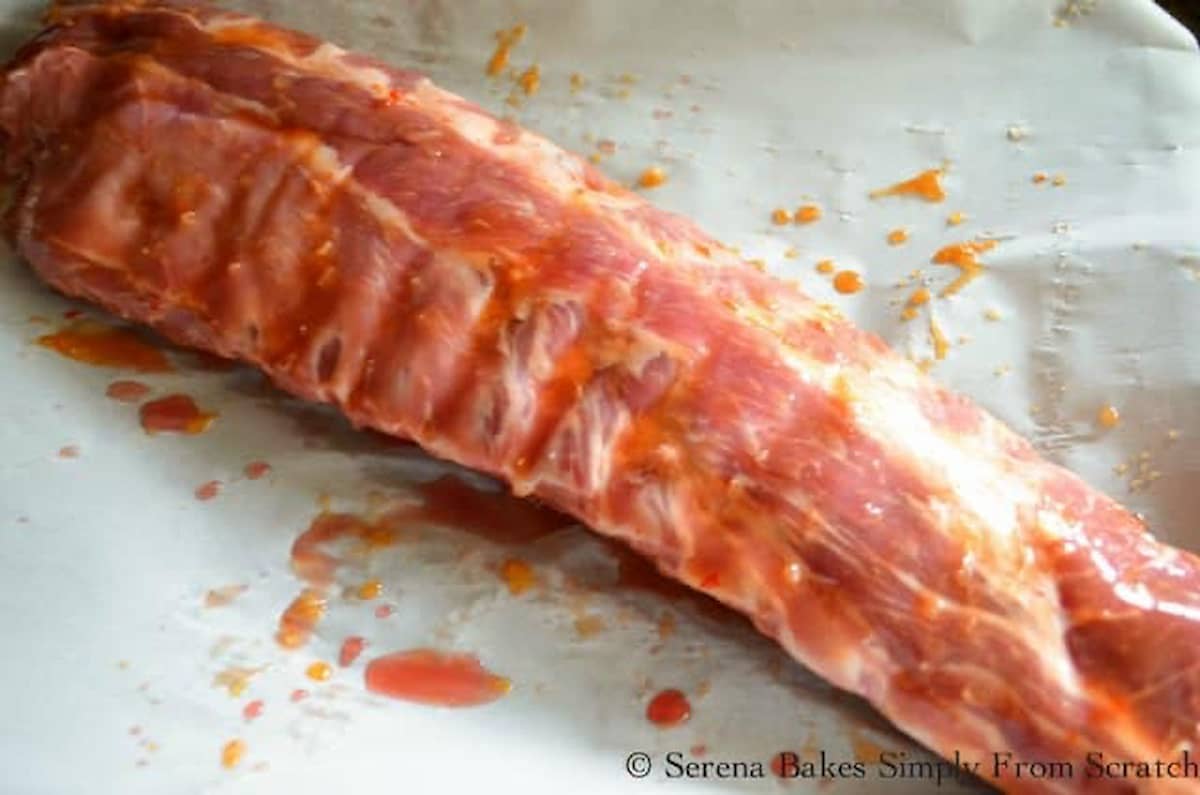 Uncooked Baby Back Ribs brushed with Sweet and Sour Sauce.