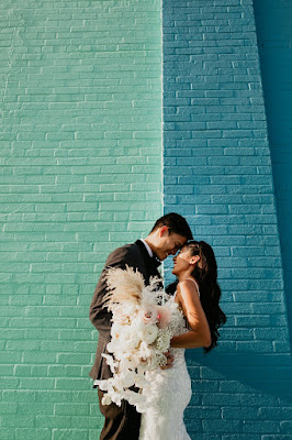bride and groom touching foreheads in front of colorful wall