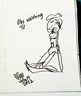 A photograph of a pen drawing in a sketchbook. The drawing vaguely resembles a scribbled person sitting, with the notation "Alex watching TV".