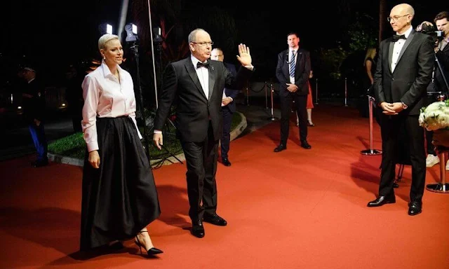 Princess Charlene wore a white silk shirt by Akris, and black pleated wide-leg skirt by Brunello Cucinelli. Dior pearl tribales earrings