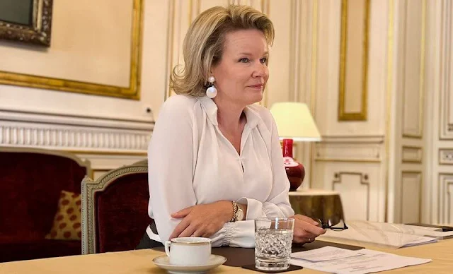 Queen Mathilde wore a striped midi skirt by Natan. White earrings. Olena Zelenska wore a green silk shirt