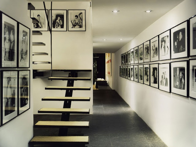 Photo of hallway with black and white minimalist staircase and lots of black and white photos on the walls