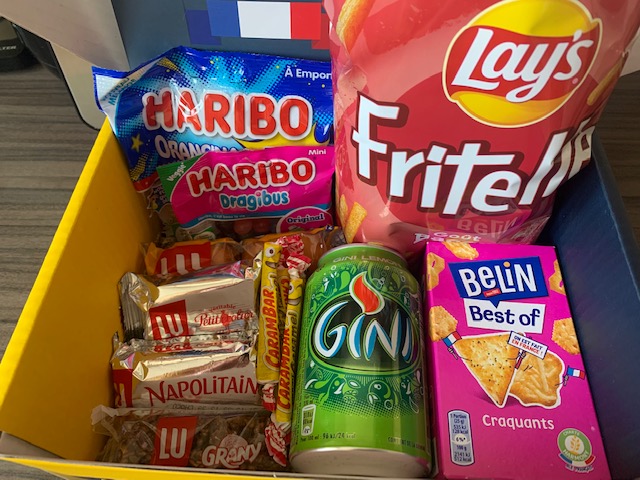 Box containing sweet and savoury snacks from France, including sweets, crisps and cake