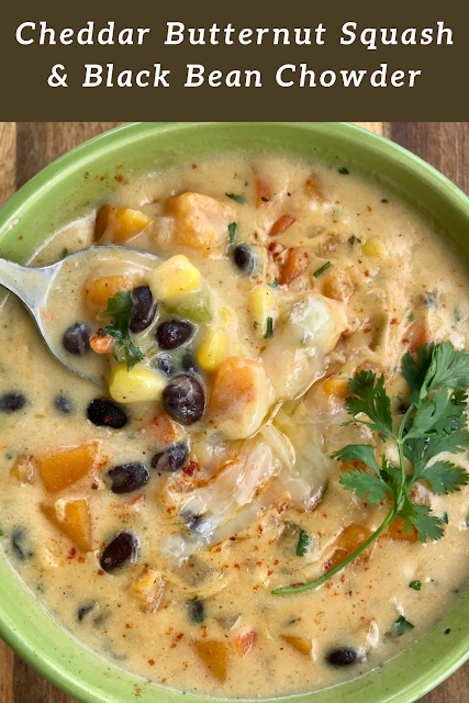 Close-up of a spoon taking a bite of cheddar butternut squash and black bean chowder from a serving bowl.