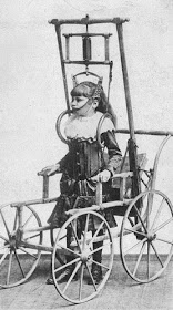 Vintage black and white photo of a young girl in a complex wheeled standing frame