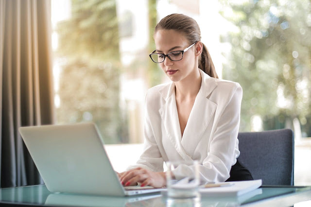 Emprendedora concentrada, tecleando en su laptop en el lugar de trabajo. Representando la importancia de qué es una VPN.