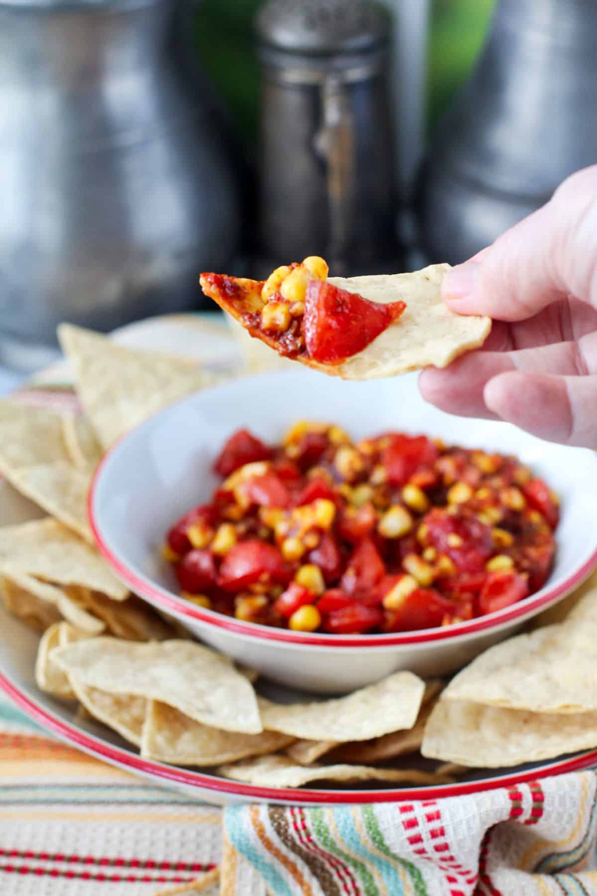 Tomato and Corn Chipotle Salsa in a bowl surrounded by corn chips.