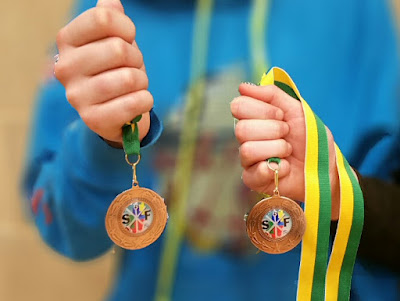 Two hands holding two bronze medals. Thame Duellists Fencing Club Southern Regional medals haul 2018-01-21 