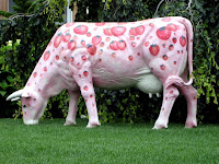 large fiberglass cow painted pink with large strawberries all over it