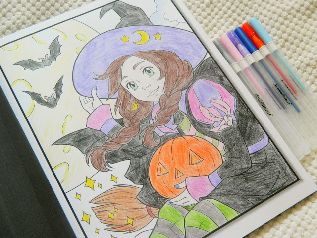 A completed colouring page of a witch holding a jack-o-lantern and some bats in the background