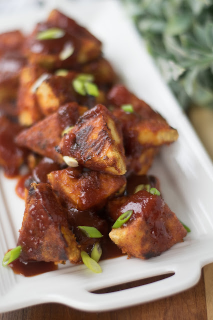 A white tray of the crispy oven baked tofu with green onions on top.