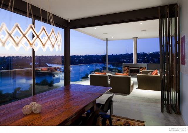 Dining room and terrace at night at River House by MCK Architects