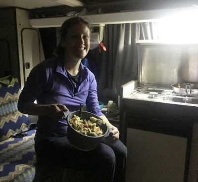 woman traveler cooking pasta in van RV camping