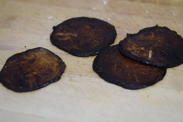 The seasoned and pressed mushrooms on a cutting board.