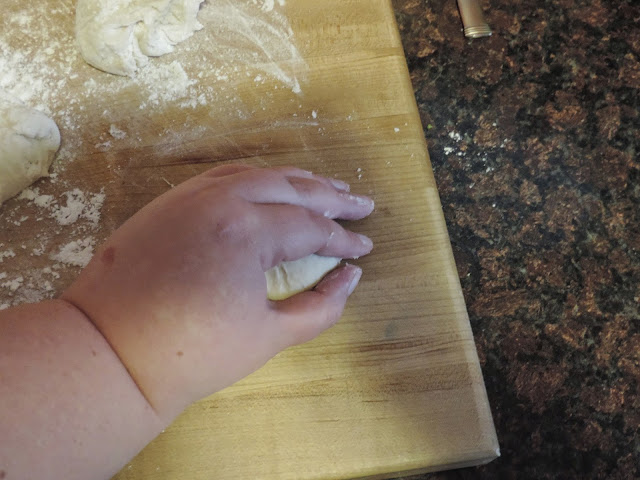 The dinner roll dough balls being rolled into nice smooth balls.