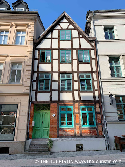 Three storey half– timbered house with a bright green entrance door and window frames painted in light green.