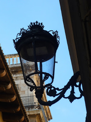 Primer plano de una farola antigua, con el Palau de la Generalitat de Valencia de fondo