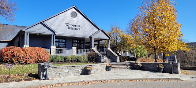 Gray building, blue sky, yellow and orange foliage on trees and shrubs.