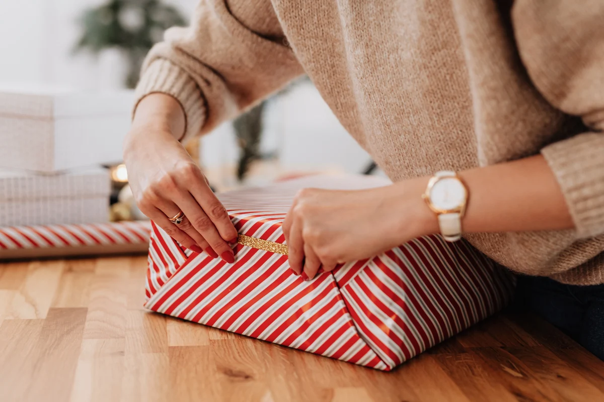 two female hand wrapping a gift box on a table