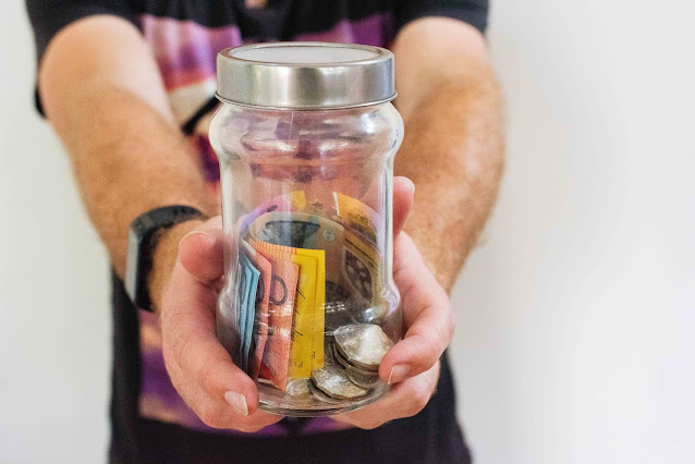 person holding jar of different kinds of money