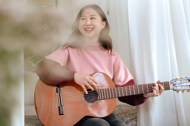 A woman smiles and holds her guitar