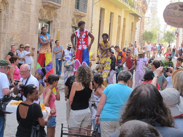 Street artists on stilts dancing and playing music for the visitors in Habana Vieja. Note the lady in the foreground selling small triangles of puff paste filled with guava jam.