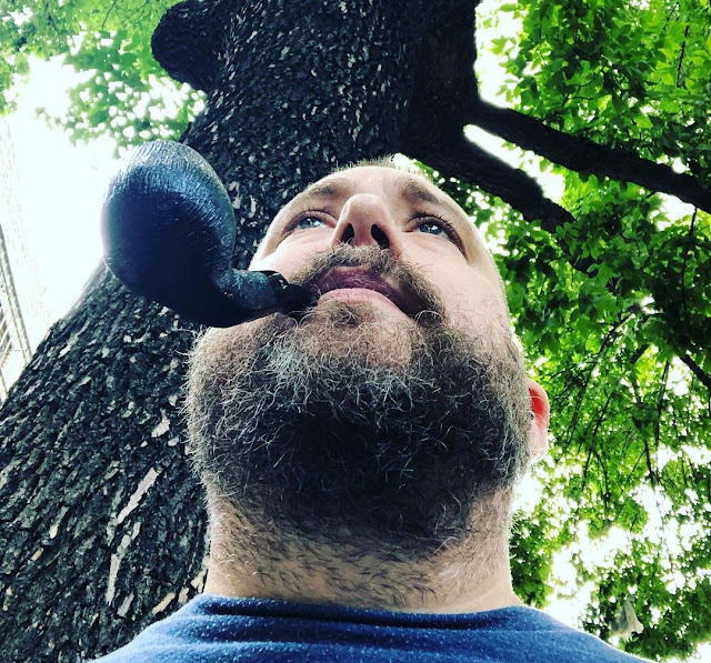 Superior view from chin up of a bear bearded sexy man with a pipe in his mouth