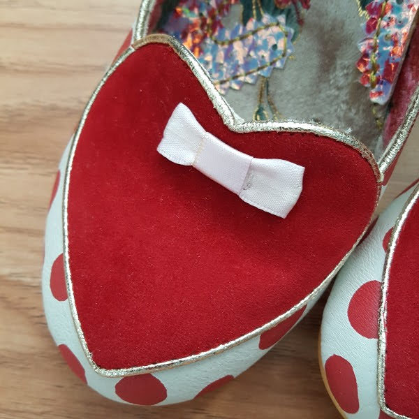 close up of suede red heart shape on front of shoe with small pink bow